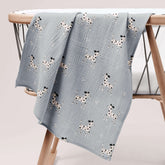 Dalmatian print muslin swaddle folded on wooden baby stand